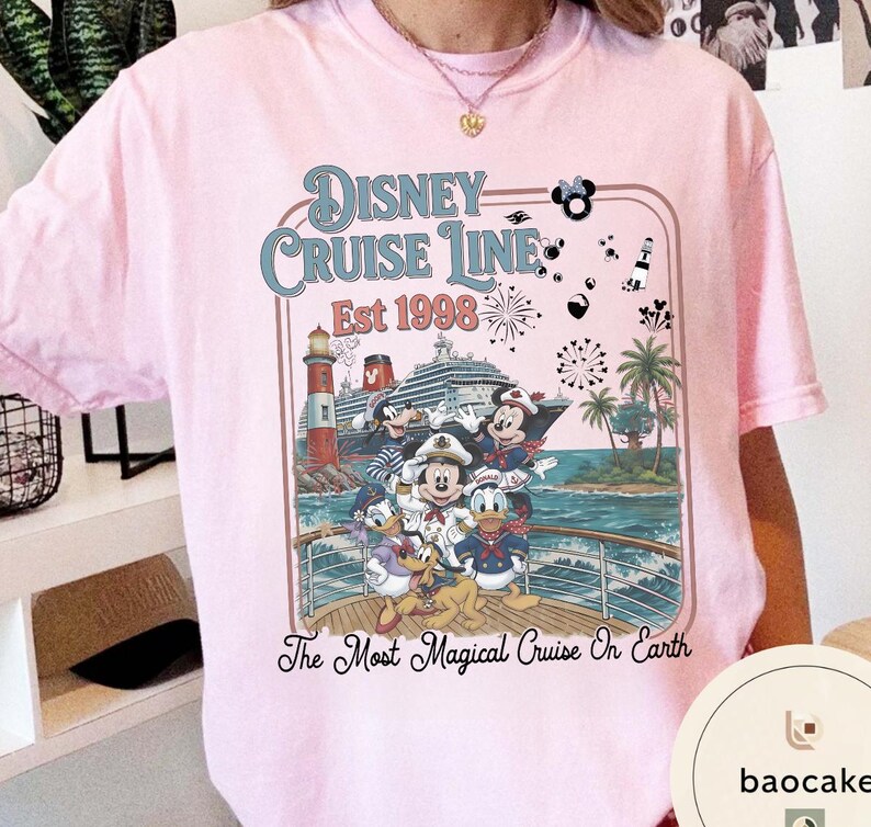 Puede incluir: Camiseta rosa claro con un dise&ntilde;o de Disney Cruise Line. El dise&ntilde;o incluye a Mickey Mouse, Minnie Mouse, Donald Duck y Goofy en un crucero, con el texto "Disney Cruise Line Est 1998" y "The Most Magical Cruise On Earth."