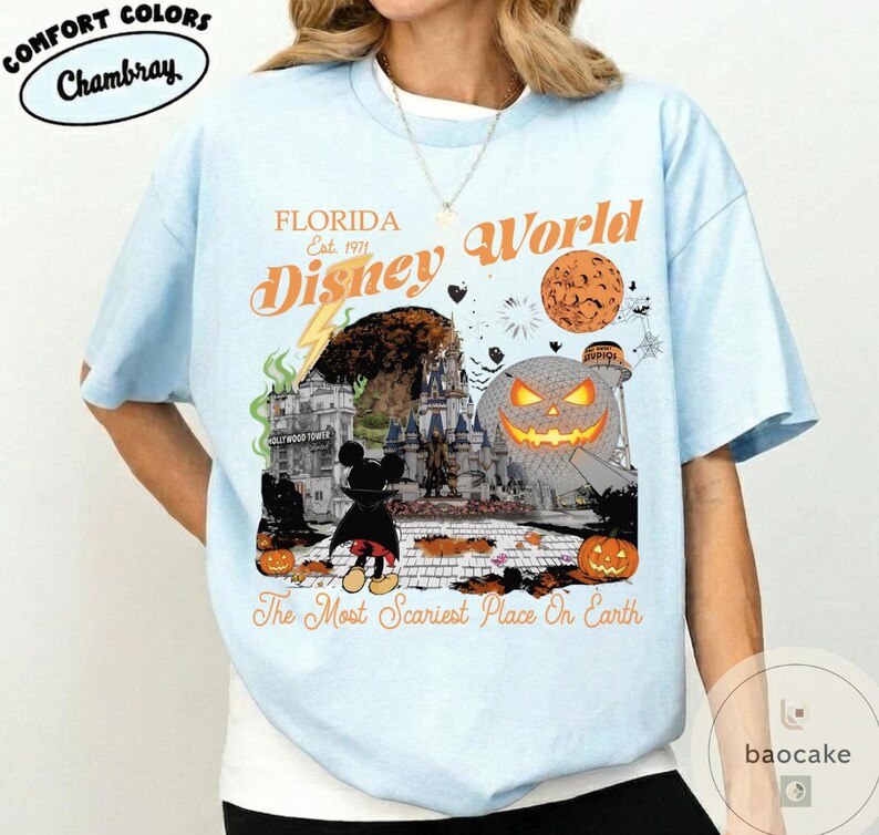 May include: Light blue t-shirt with a graphic featuring "Florida Disney World" and a Halloween theme. The design includes a castle, Mickey Mouse, pumpkins, and the text "The Most Scariest Place On Earth."