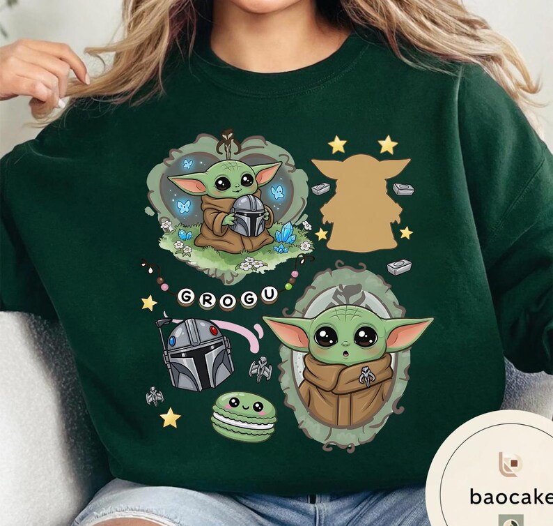 May include: A dark green crewneck sweatshirt featuring a graphic print of Grogu from Star Wars. The design includes Grogu holding a helmet, a silhouette, a portrait in a frame, a silver helmet, a green macaron, and the text GROGU on a banner.