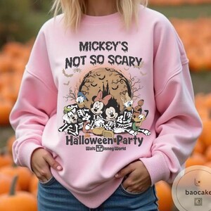 May include: A light pink sweatshirt with the text "Mickey's Not So Scary Halloween Party" and Disney characters in skeleton costumes. The graphic includes Mickey, Minnie, Donald, Daisy, Goofy, and Pluto. The Walt Disney World logo is at the bottom.