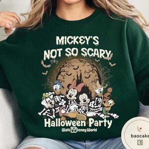 May include: Dark green sweatshirt featuring a Halloween-themed graphic. The design includes Mickey Mouse, Minnie Mouse, Donald Duck, Daisy Duck, and Goofy dressed as skeletons. The text "Mickey's Not So Scary Halloween Party" is printed above the characters.