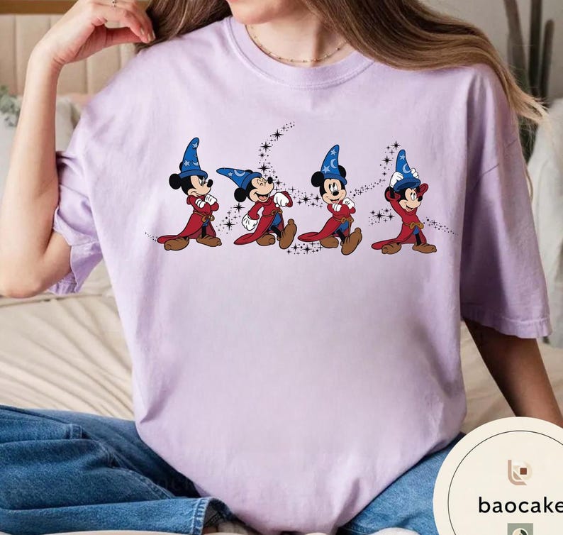 May include: A light purple t-shirt featuring a graphic of Mickey Mouse in a sorcerer's outfit, with a blue hat and red robe. The design shows Mickey in four different poses, with a starry trail.