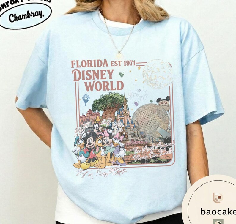 May include: A light blue t-shirt featuring a graphic print with the text FLORIDA EST 1971 DISNEY WORLD and The Most Magical Place On Earth. The design includes illustrations of Disney characters, the Tree of Life, and the Epcot geodesic sphere.