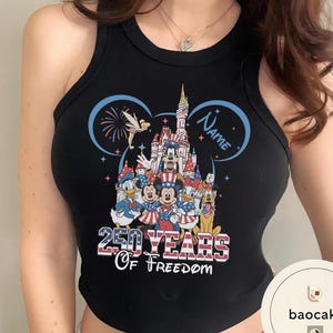 Peut inclure: D&eacute;bardeur noir avec un graphisme color&eacute; de personnages Disney, dont Mickey Mouse et Donald Duck, devant un ch&acirc;teau. Le texte "250 Years of Freedom" est affich&eacute; en dessous des personnages, avec un design bleu et rouge.