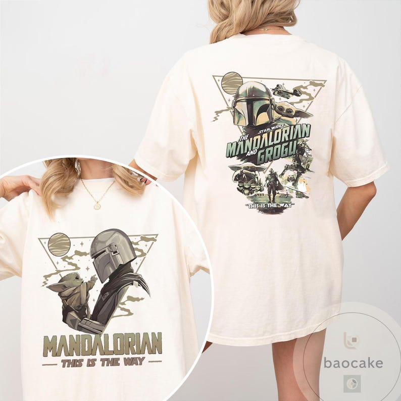 Op de afbeelding: Cr&egrave;mekleurig T-shirt met een afbeelding van The Mandalorian en Grogu. Het ontwerp aan de voorkant toont de Mandalorian en Grogu met de tekst "MANDALORIAN - THIS IS THE WAY". Het ontwerp aan de achterkant bevat de tekst "STAR WARS THE MANDALORIAN AND GROGU".