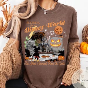 May include: Brown t-shirt with a graphic featuring a Halloween-themed Disney World scene. The design includes a jack-o'-lantern, Mickey Mouse, and the text "Florida Disney World" and "The Most Scariest Place On Earth."