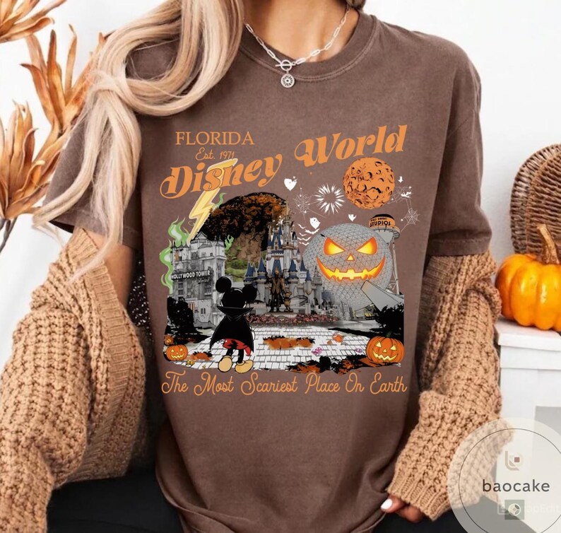 May include: Brown t-shirt with a graphic featuring a Halloween-themed Disney World scene. The design includes a jack-o'-lantern, Mickey Mouse, and the text "Florida Disney World" and "The Most Scariest Place On Earth."