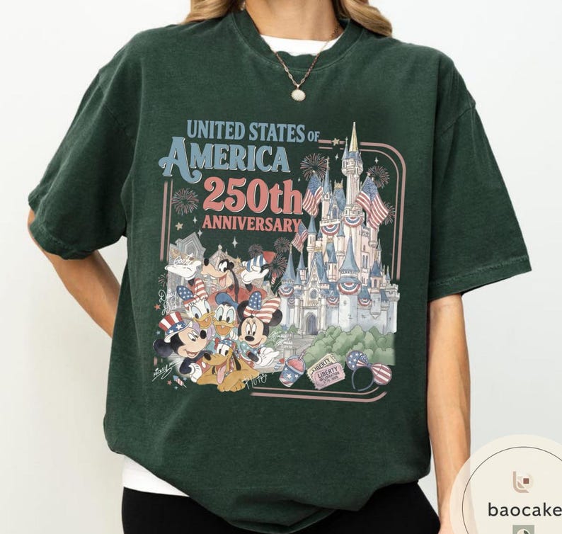 May include: Dark green t-shirt featuring a graphic celebrating the 250th anniversary of the United States of America. The design includes a castle, fireworks, and cartoon characters like Mickey Mouse and Donald Duck.