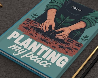 Può includere: Un diario turchese con le parole "PLANTING my peace" in bianco. La copertina presenta un'illustrazione di mani che piantano una piantina. Matite dorate e nere e fermagli dorati sono sulla superficie grigio scuro.