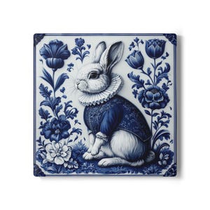 Könnte beinhalten: Quadratische Keramikfliese mit einem weißen Kaninchen in einer blauen Jacke und Rüschenkragen, vor blauem Blumendekor. Das Design hat eine klassische, Vintage-Ästhetik, geeignet für die Inneneinrichtung. Die Fliese misst ca. 20 cm x 20 cm.