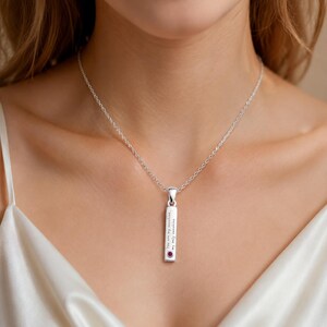 Può includere: Una collana con pendente in argento con un ciondolo rettangolare. Il ciondolo ha l'iscrizione "You are my sunshine, my only sunshine" e una piccola gemma rossa rotonda. La collana è indossata al collo.