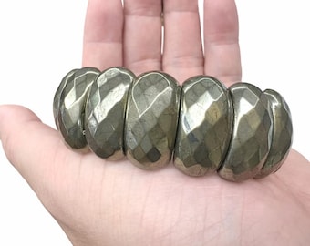 May include: A stretch bracelet composed of six large, faceted, metallic pyrite beads. Each bead features a reflective, gunmetal-colored surface with a geometric, multi-faceted cut that creates a textured appearance across the entire piece.