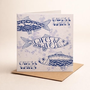 Tarjeta de cerámica de pez azul marino, ilustración de la costa de Cumbria, tarjeta de felicitación en blanco con cuevas y olas