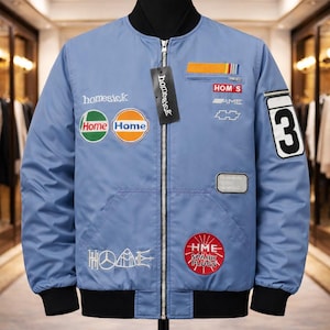 May include: Light blue bomber jacket with black trim and multiple embroidered patches. Patches include the words "homesick", "Home Home", "HME Spark Plugs", and the number "3". The jacket has a zipper closure and two front pockets.