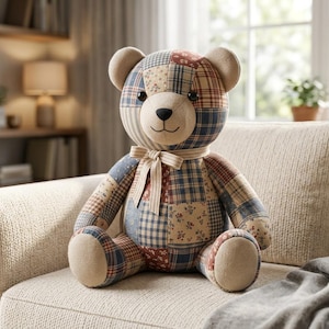 Peut inclure: Un ours en peluche fabriqué à partir de divers morceaux de tissu dans des tons de bleu, rouge et beige. L'ours présente un museau beige, des yeux en boutons foncés, un nez et une bouche cousus, et un ruban en tissu rayé noué autour du cou.