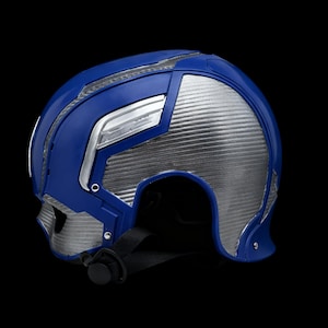 May include: A blue and silver helmet with a black chin strap. The helmet features a futuristic design with silver panels and blue accents. The helmet is made of plastic and has a glossy finish.