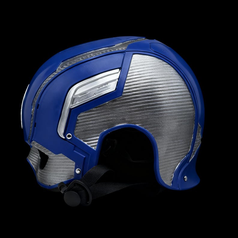May include: A blue and silver helmet with a black chin strap. The helmet features a futuristic design with silver panels and blue accents. The helmet is made of plastic and has a glossy finish.