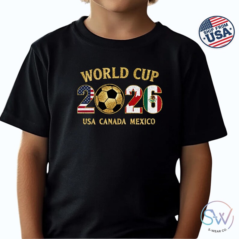 May include: Black t-shirt with a gold design featuring the text "WORLD CUP 2026" and a soccer ball. The numbers 2026 are filled with the USA, Canada, and Mexico flags. The text "USA CANADA MEXICO" is below the numbers.