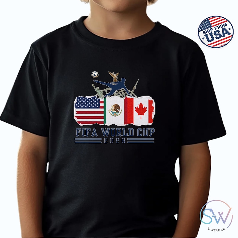 May include: Black t-shirt featuring the text "FIFA WORLD CUP 2026" below a graphic of a soccer player kicking a ball, with the flags of the USA, Mexico, and Canada. A soccer ball and an eagle are also in the graphic.