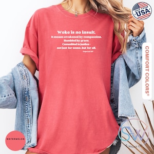 May include: A watermelon-colored t-shirt with the text "Woke is no insult." in white. The shirt also features a quote by Pope Leo XIV. The shirt is part of the Comfort Colors collection.