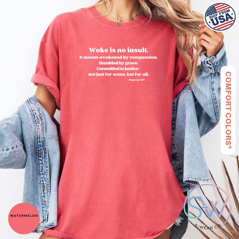 May include: A watermelon-colored t-shirt with the text "Woke is no insult." in white. The shirt also features a quote by Pope Leo XIV. The shirt is part of the Comfort Colors collection.
