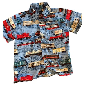 May include: Short-sleeved button-down shirt with a light blue background and a repeating pattern of vintage train cars in red, brown, and white. The shirt has a collared neckline and a pocket on the chest.