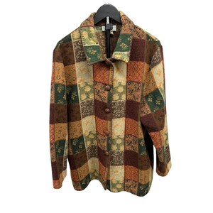 May include: A patchwork jacket in shades of brown, green, and orange, with a button-up front and a collared neckline. The jacket features a variety of patterned squares, creating a unique and textured design. The jacket is hanging on a black hanger.