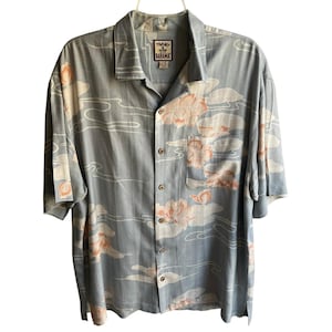 以下が含まれることがあります： ピーチと白の花柄のライトブルーのボタンダウンシャツ。 シャツは半袖、胸ポケット、"Tommy Bahama"ブランドラベルが付いています。 シャツは白いハンガーにかかっています。