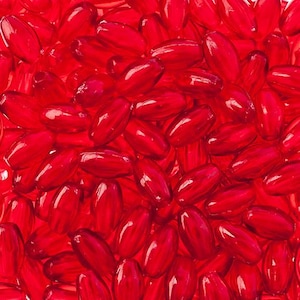 May include: A close-up image of a pile of red glass beads. The beads are oval shaped and have a glossy finish.
