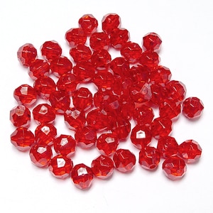 May include: A pile of red faceted glass beads. The beads are round and have a shiny finish.