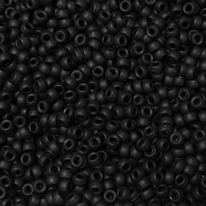 May include: A close-up image of a large quantity of black round beads. The beads are all the same size and shape, and they are arranged in a random pattern.