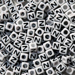 May include: A large quantity of white plastic letter beads with the letter "Z" printed in black on each bead.