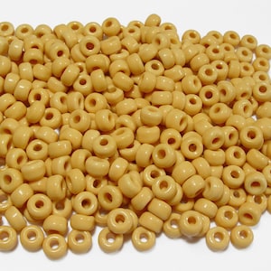 May include: A large pile of small, round, yellow ceramic beads. The beads have a hole in the center for stringing.