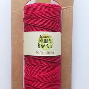 May include: A spool of red hemp cord from Bead Smith Natural Elements, 197 ft (60 m), 20 lb (9 kg). The product is packaged on a brown cardboard backing with the brand name and product details printed on it.