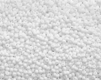 May include: A close-up image of a large quantity of small, white, round seed beads. The beads are arranged in a random pattern, creating a textured surface.