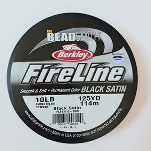 May include: A spool of black FireLine fishing line by Berkley. The spool is labeled "Black Satin" and has a 10lb test and 125yd capacity. The label also includes the text "Smooth & Soft" and "Permanent Color".