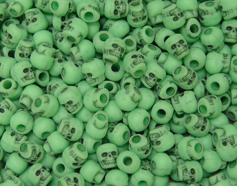 May include: A large pile of green plastic skull beads. The beads are all the same size and shape, and they are arranged in a random pattern.