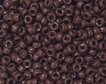 Op de afbeelding: Een grote hoeveelheid bruine plastic kralen. De kralen zijn rond en hebben een gat in het midden.