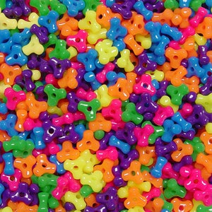 May include: A close-up of a large pile of colorful plastic beads. The beads are shaped like a three-pointed star with a hole in the center. The beads are in a variety of colors, including red, orange, yellow, green, blue, purple, and pink.