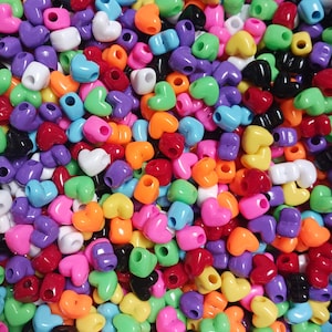 May include: A large assortment of colorful heart-shaped plastic beads. The beads are in a variety of colors, including red, orange, yellow, green, blue, purple, pink, and black.