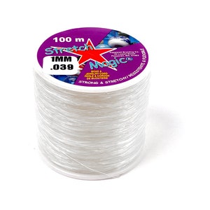 May include: A spool of clear, stretchy beading cord. The label reads "Stretch Magic" and includes the measurements "100 m" and "1MM / .039". The cord is designed for bead and jewelry making. The label is purple, red, and white.