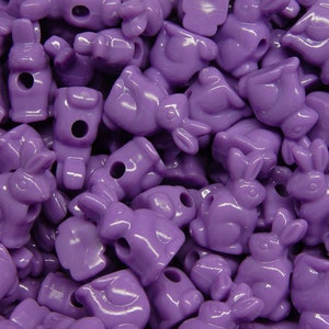 May include: A large pile of purple plastic bunny-shaped beads. The beads have a hole through the center for stringing.