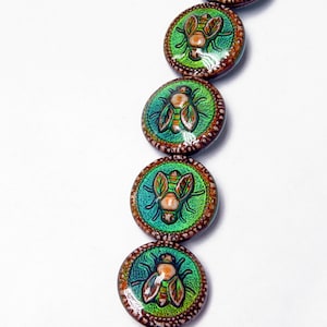May include: A string of round, green and brown glass beads with a raised image of a fly on each bead.