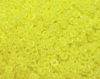 Op de afbeelding: Een grote hoeveelheid kleine, ronde, doorschijnende gele plastic kralen. De kralen zijn allemaal even groot en even gevormd en zijn in een willekeurig patroon gerangschikt.