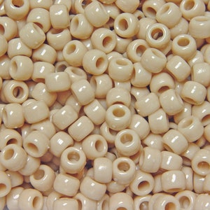 May include: A large quantity of off-white plastic beads. The beads are round with a hole in the center.