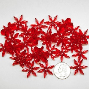 May include: A group of 20 red plastic star-shaped ornaments. The ornaments are about the size of a US quarter.
