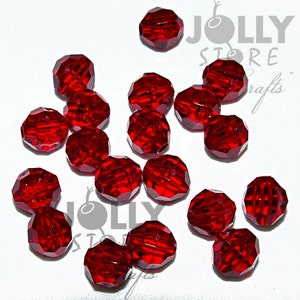 May include: A group of 16 red faceted glass beads. The beads are round and have a shiny finish. They are scattered on a white surface.
