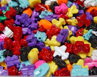 May include: A large collection of colorful plastic toy beads in the shapes of airplanes, cars, trains, and other vehicles. The beads are perfect for crafting and making jewelry.