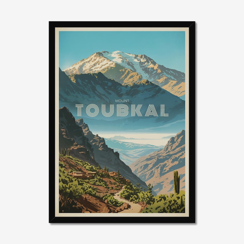 Peut inclure: Une impression d'art encadr&eacute;e repr&eacute;sentant un paysage stylis&eacute; du mont Toubkal avec un sommet enneig&eacute;, des montagnes bleu fonc&eacute; escarp&eacute;es et un sentier sinueux traversant une v&eacute;g&eacute;tation verte et de petits b&acirc;timents. Le texte MOUNT TOUBKAL est centr&eacute;.