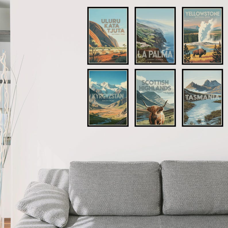 Peut inclure: Un ensemble de six affiches de voyage encadr&eacute;es illustrant Uluru Kata Tjuta, La Palma, le parc national de Yellowstone, le Kirghizistan, les Highlands &eacute;cossais avec une vache Highland et la Tasmanie, dispos&eacute;es sur deux rang&eacute;es sur un mur blanc.